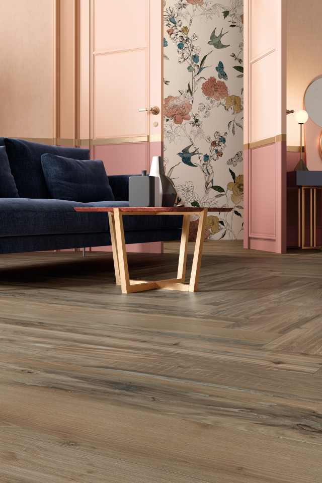 herringbone wood look tile in modern pink and gold living room next to wallpapered hallway entry